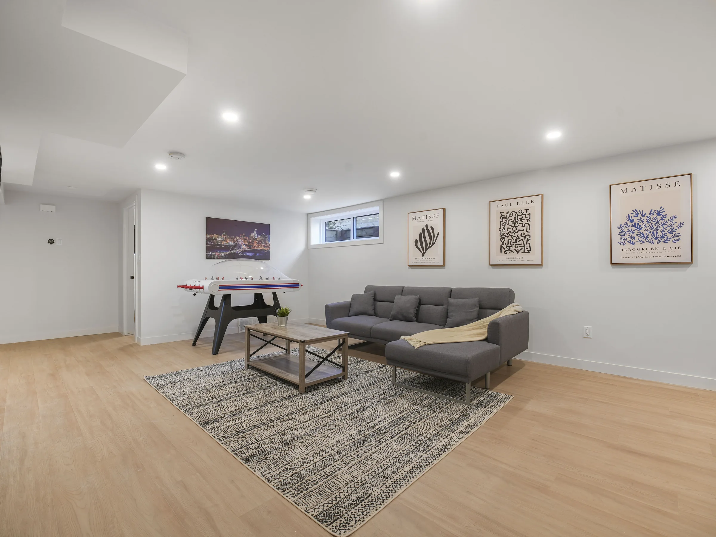 Rec-room and kitchen open space with foosball table, sectional and a gallery-wall of prints