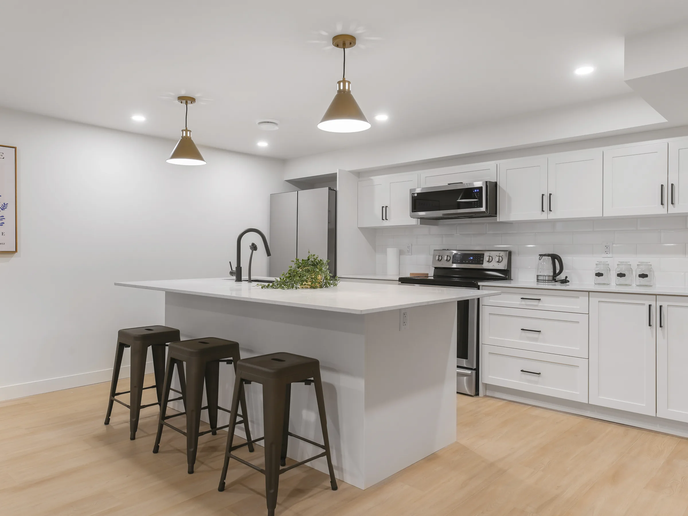 Basement kitchen wide shot with island in the foreground and tall wood cabinets on the side wall