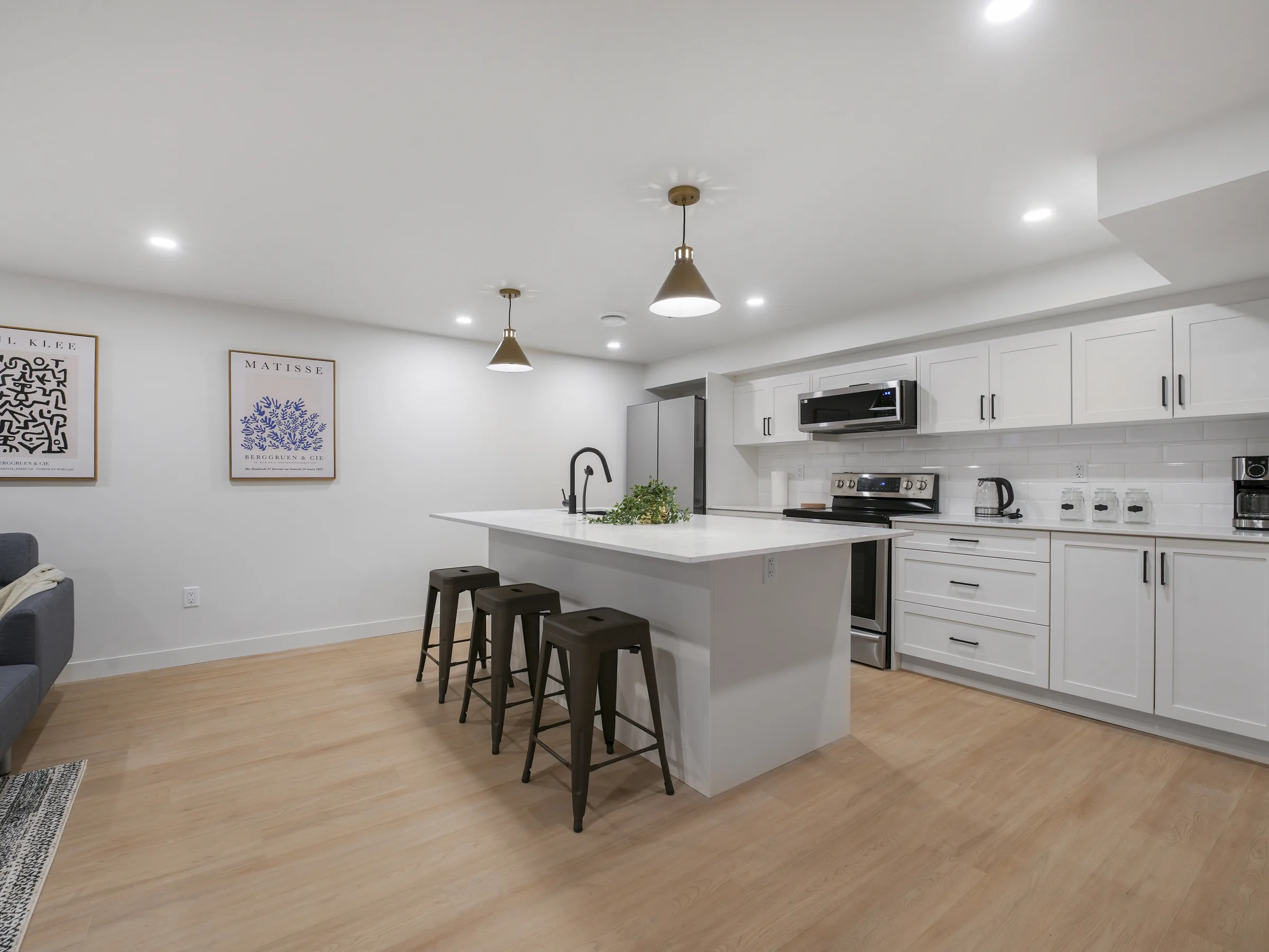 Kitchen and rec room in open layout, TV mounted on the wall, stairs visible