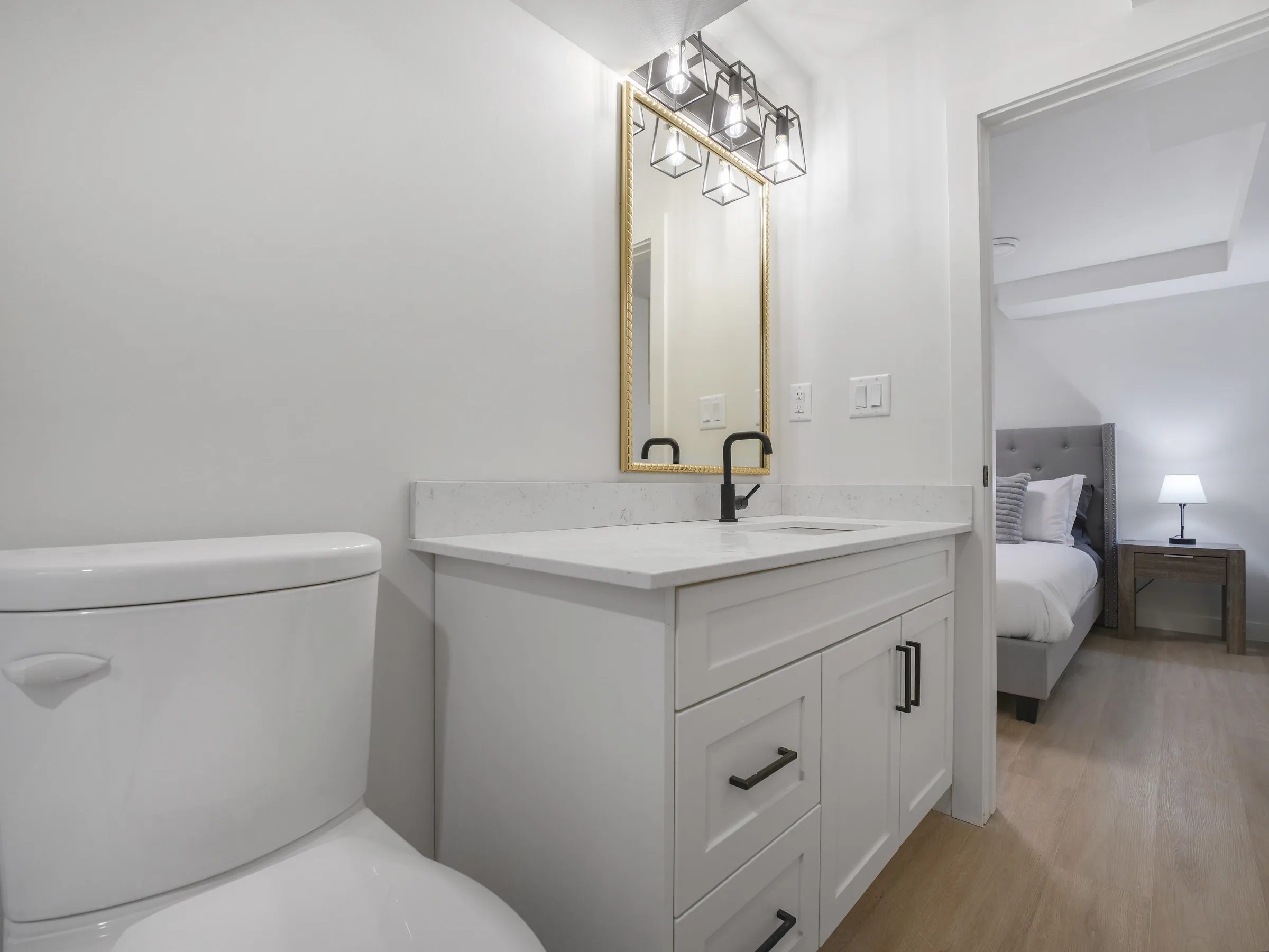 Gold-mirror vanity with view into the adjoining bedroom