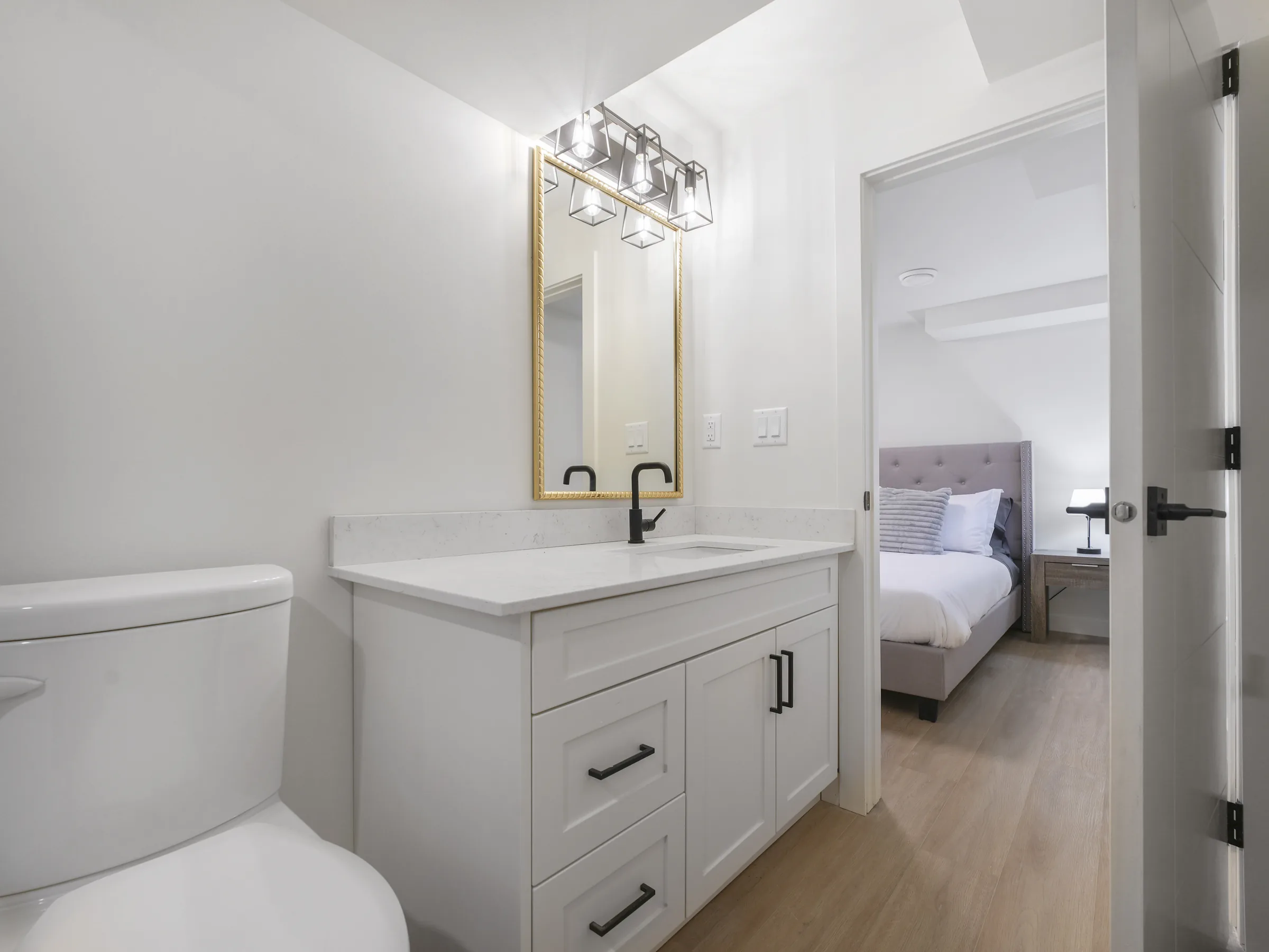 Gold-mirror vanity with a view toward the third bedroom
