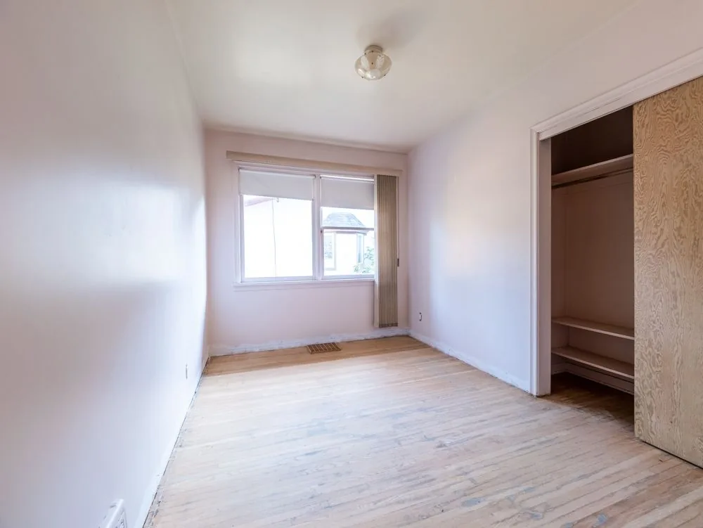 Before renovation, empty bedroom with hardwood floor and sliding closet door