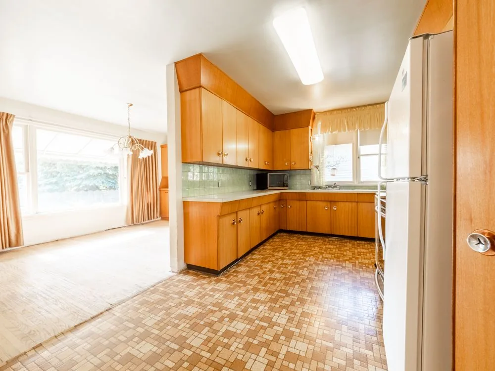 Before renovation, kitchen opening into the dining and living room, wood cabinets