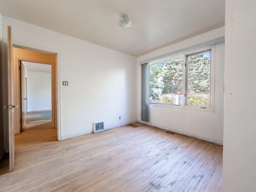 Before renovation, empty bedroom with hallway to another room, green carpet visible