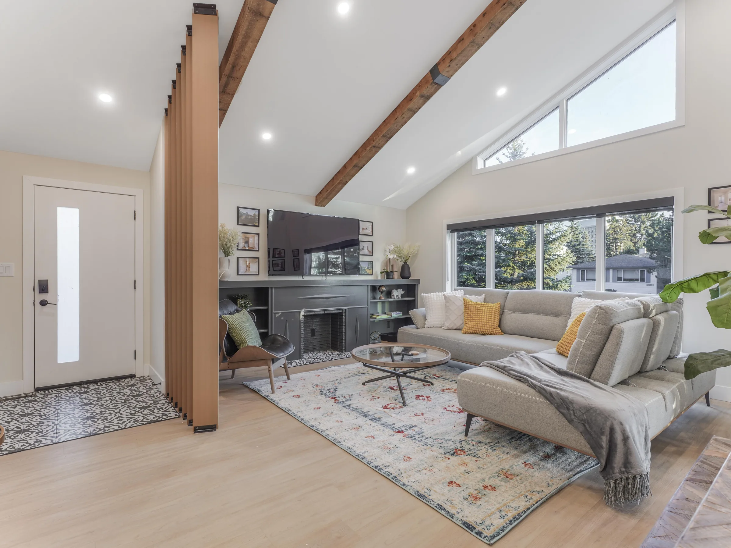 Living side of the great room with sectional sofa, entry visible, fireplace and TV
