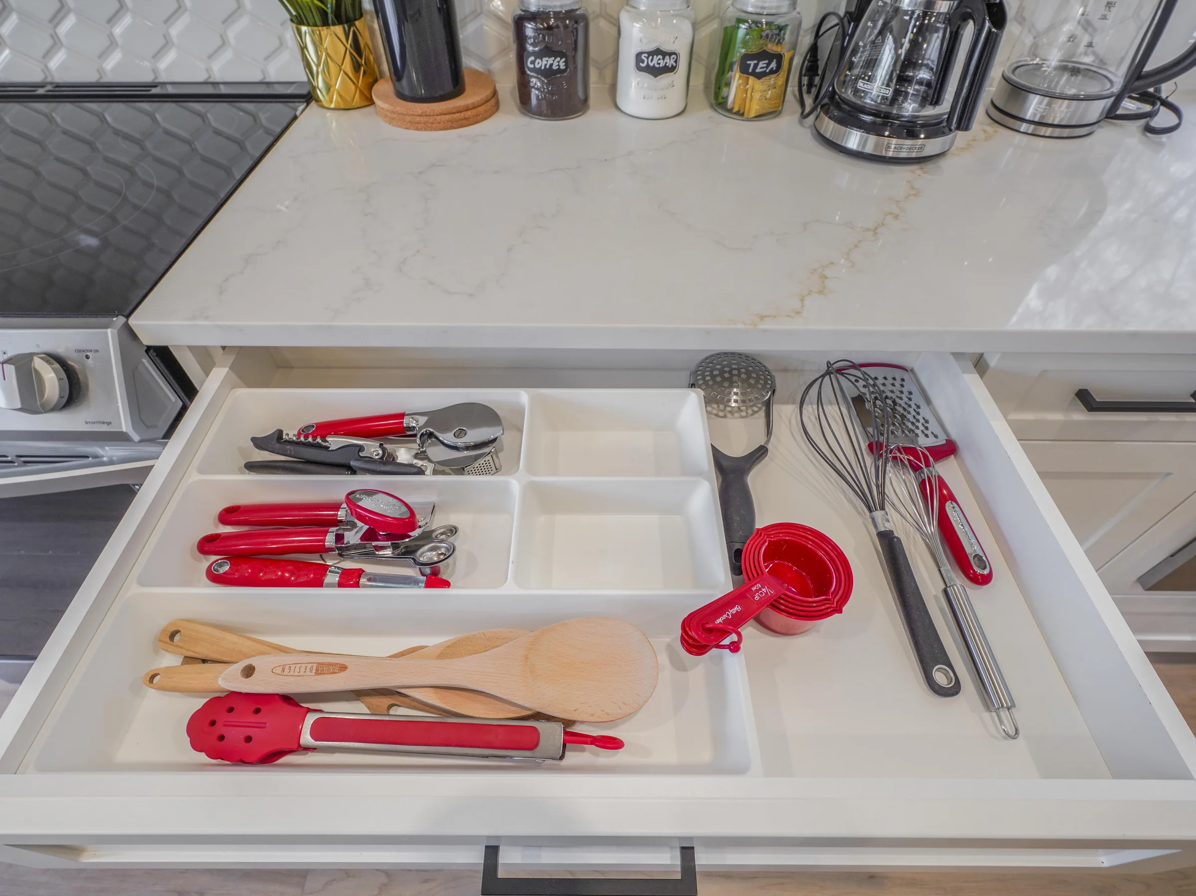 Kitchen drawer open showing red-handled utensils