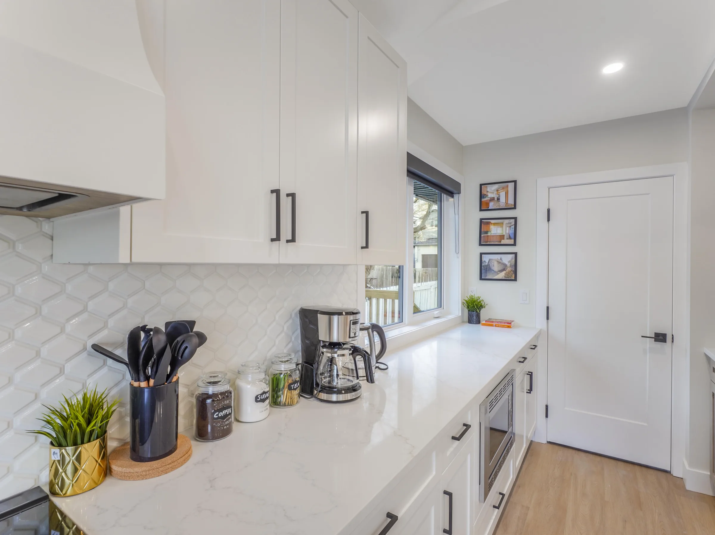 Galley view of the kitchen toward the mudroom door, framed photos on the wall