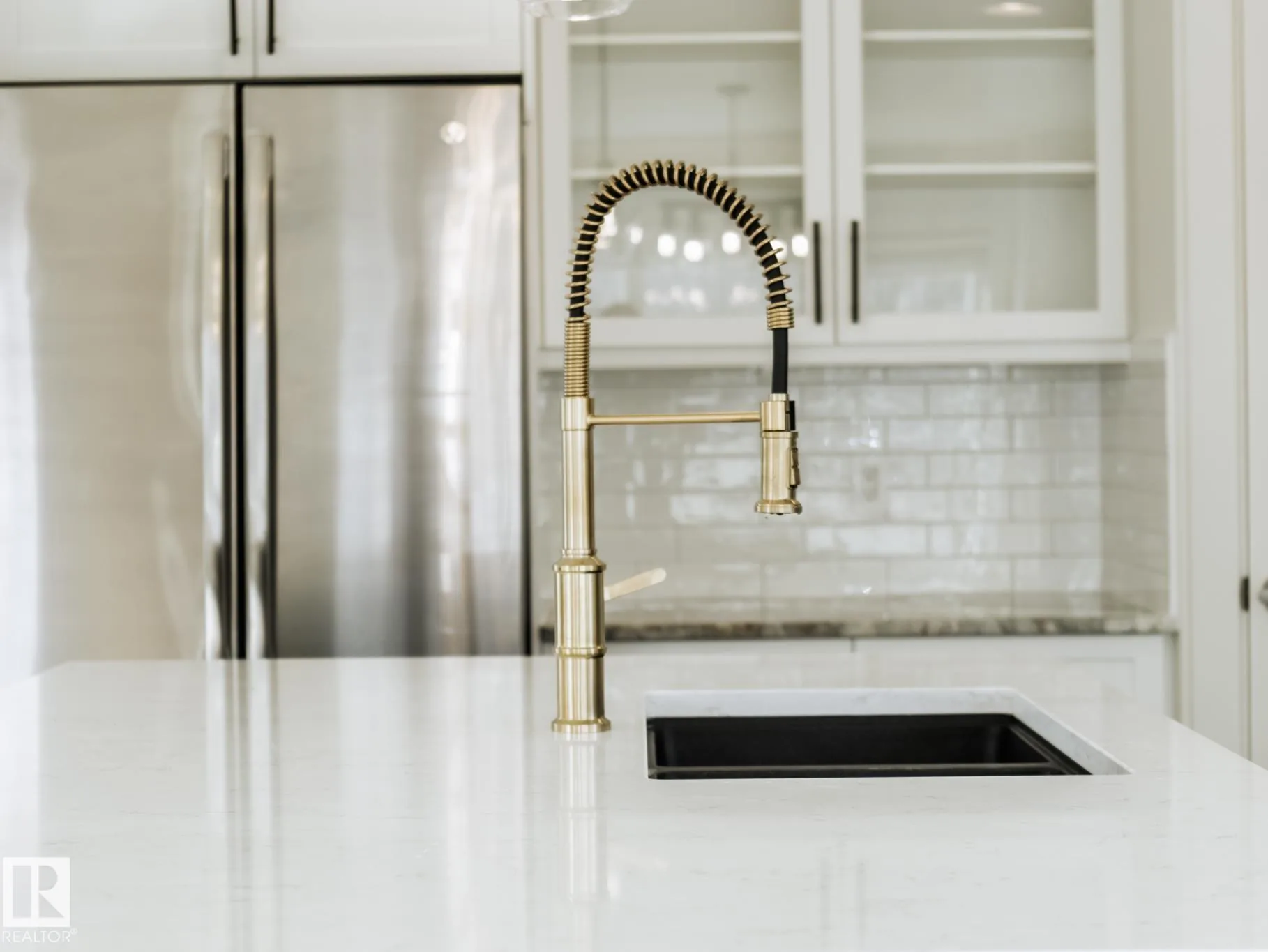 Gold spring-coil faucet against the subway-tile backsplash