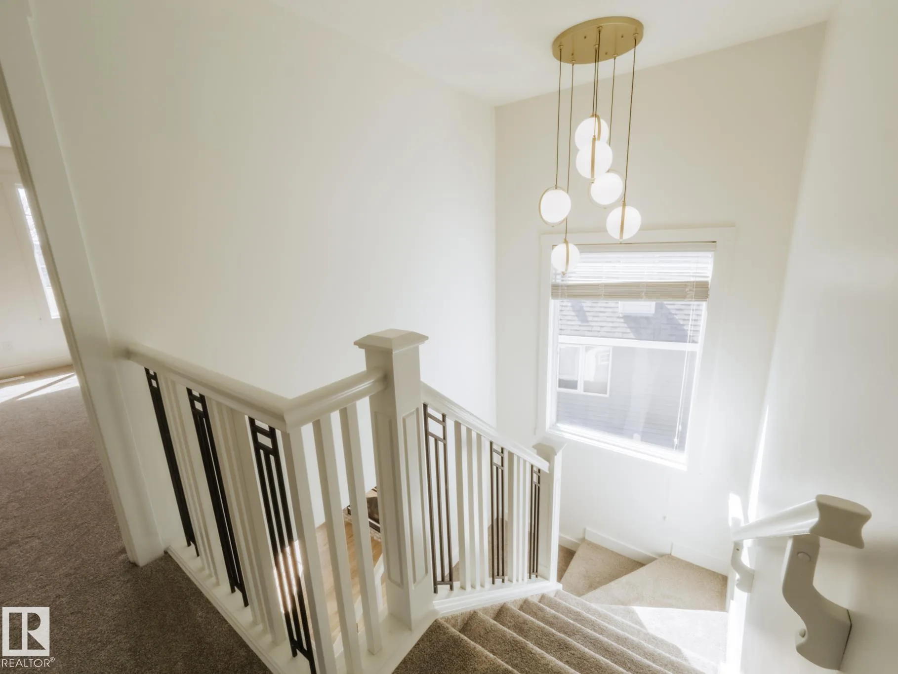 Upper stair landing with a gold multi-drop pendant over the stairwell