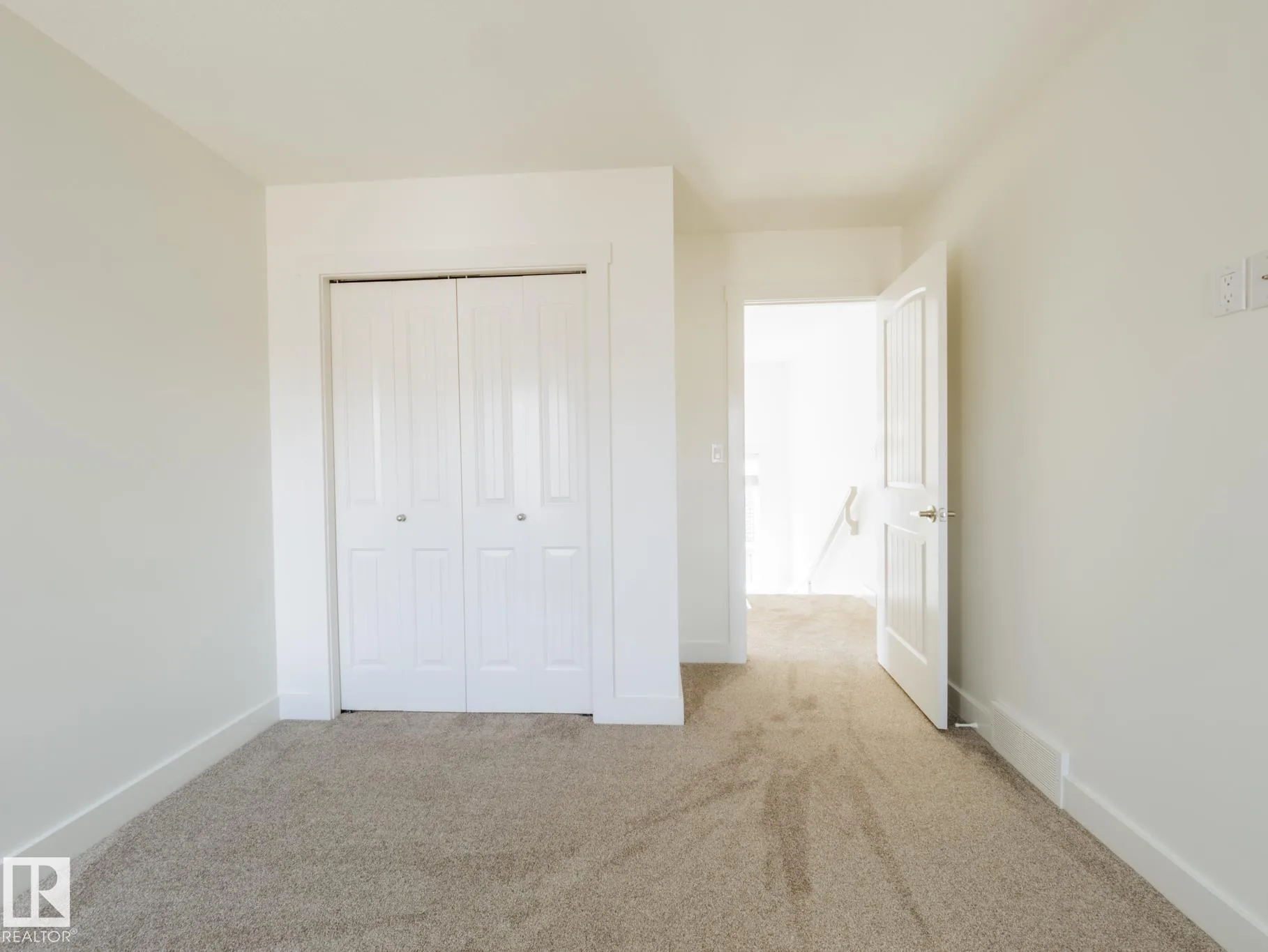 Bedroom near the top of the stairs, black-baluster railing visible through the open door