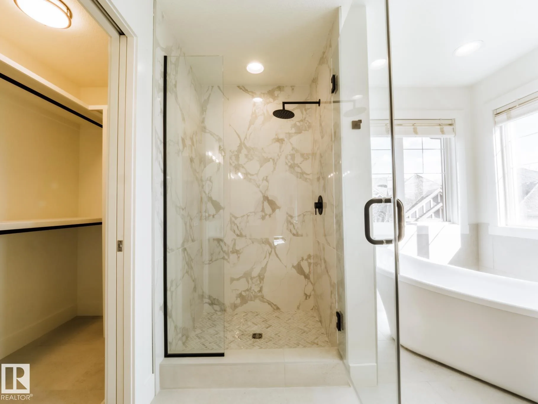 Full-height marble walk-in shower with a black rain shower head