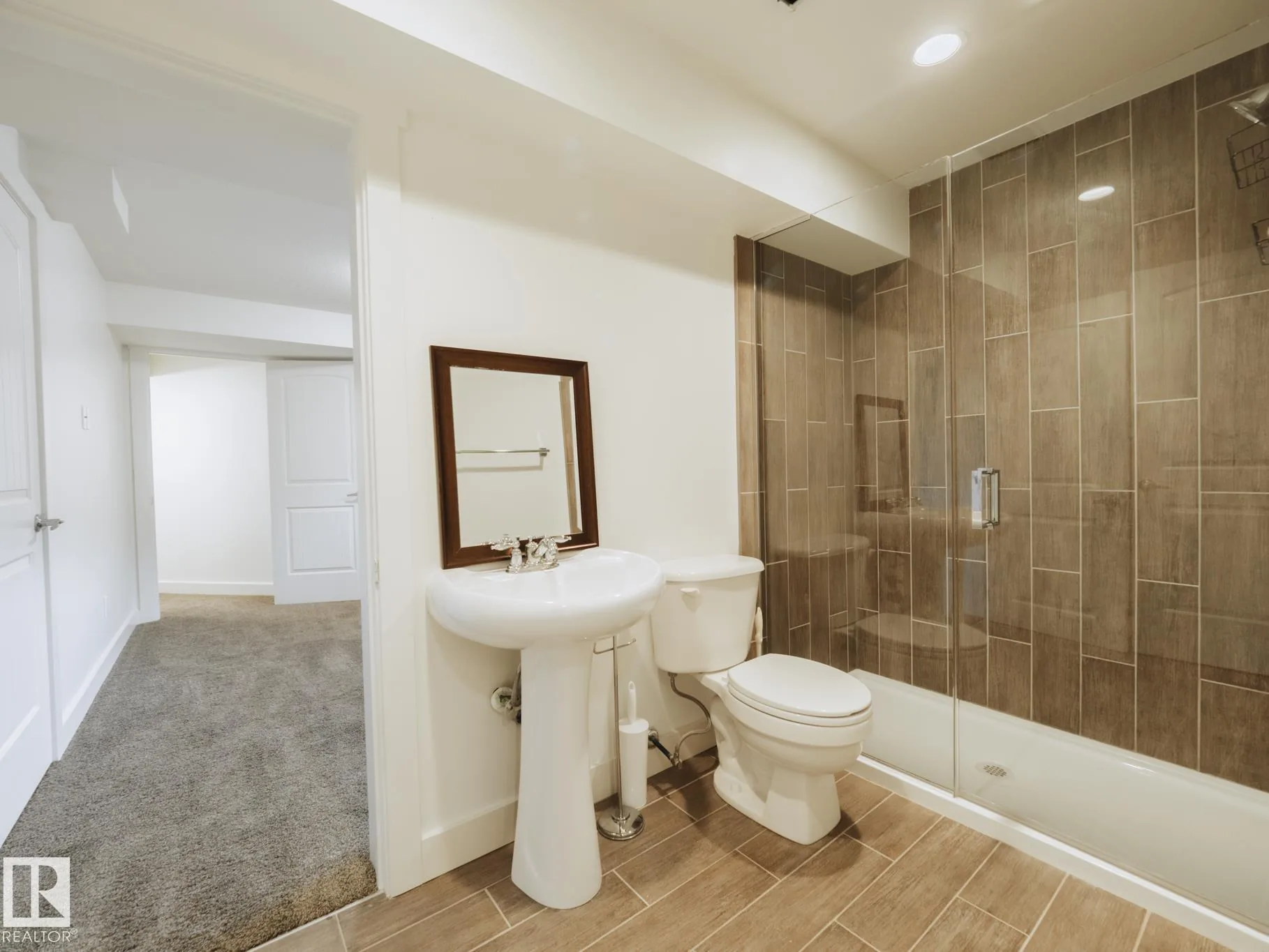 Basement bath pedestal sink opening onto the carpeted hallway