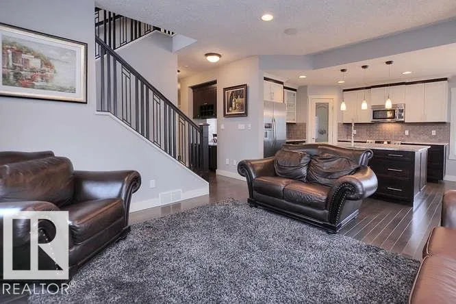 Before renovation, living room seating area with the staircase and kitchen in view
