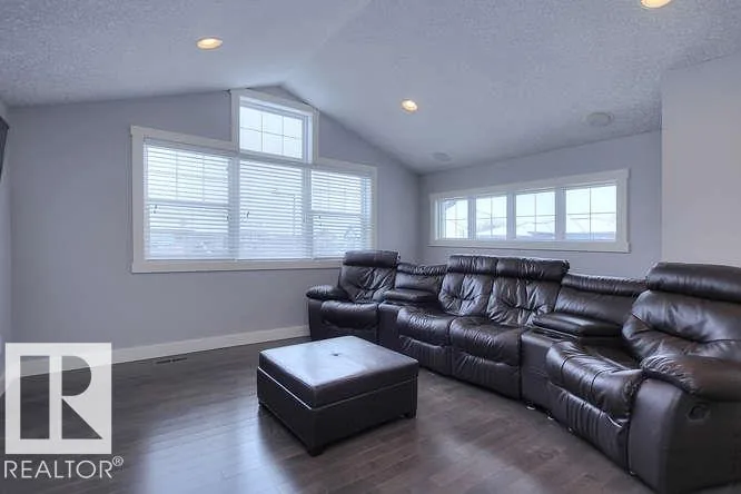 Before renovation, bonus room with a vaulted ceiling and leather sectional
