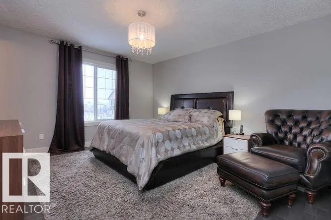 Before renovation, primary bedroom with dark wood bed and floor-length drapes