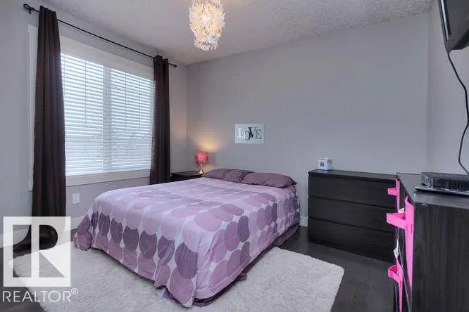 Before renovation, secondary bedroom with lavender bedding and a crystal chandelier