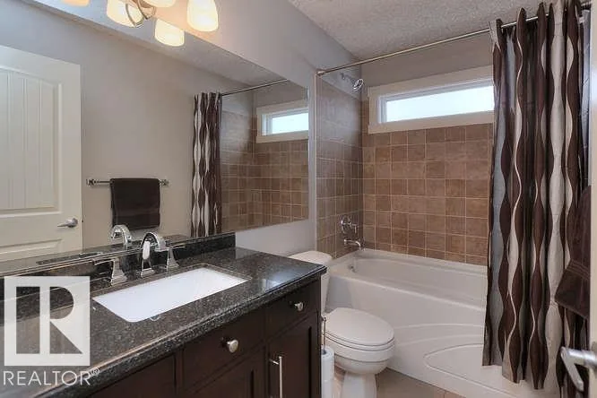 Before renovation, main bath with a dark granite vanity and window over the tub