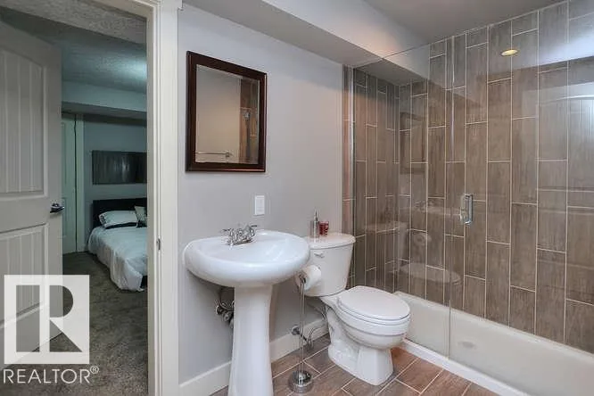 Before renovation, basement bath with pedestal sink and tiled shower