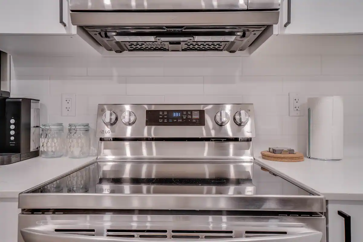 Close-up of the electric range and stainless hood insert in the suite kitchen, with glass mason jars and a coffee maker on the adjacent counter.