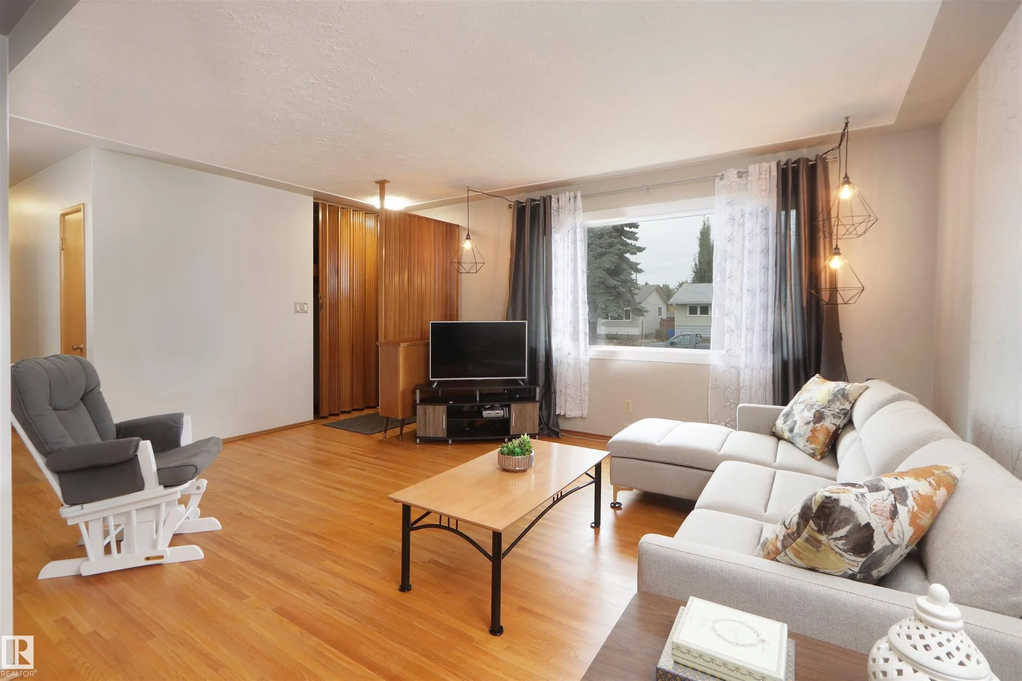 Before renovation, living room facing the front door with the wood-slat divider on the right and hardwood underfoot.