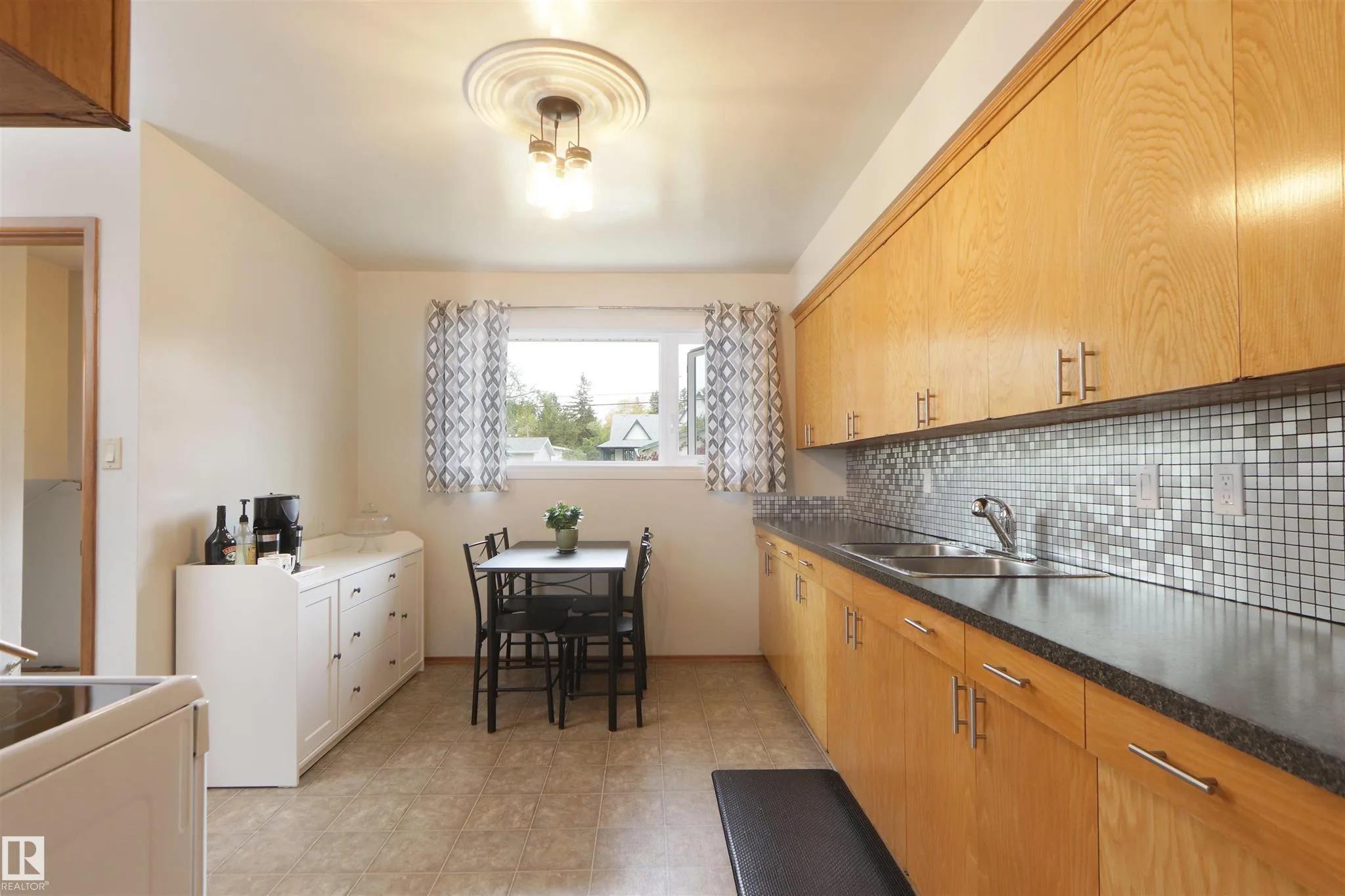 Before renovation, wider kitchen shot showing the full run of oak cabinets and the small breakfast dinette against the wall.