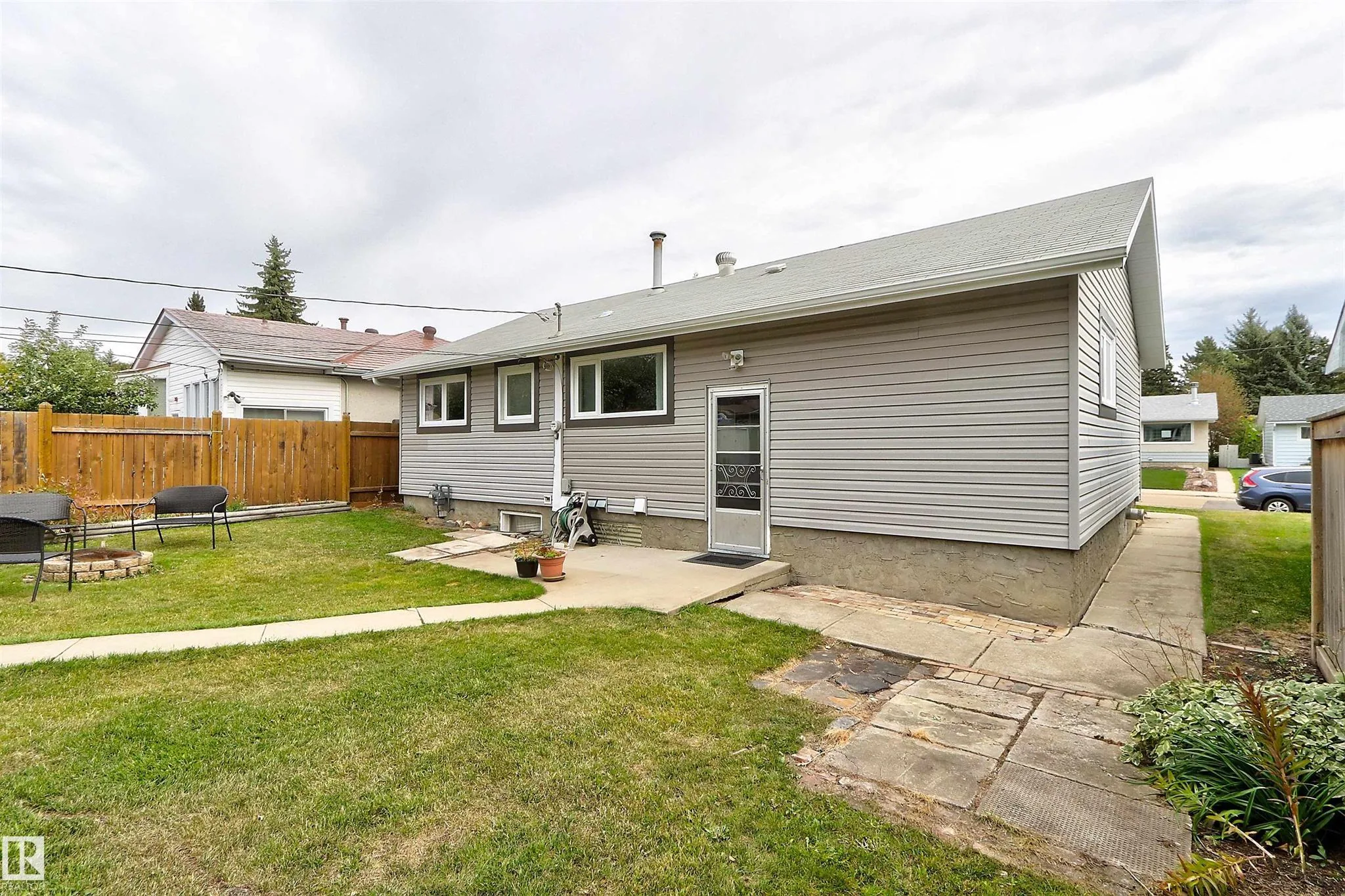 Before renovation, rear elevation from an angled side view showing the concrete stoop, back door, and gable end to the right.
