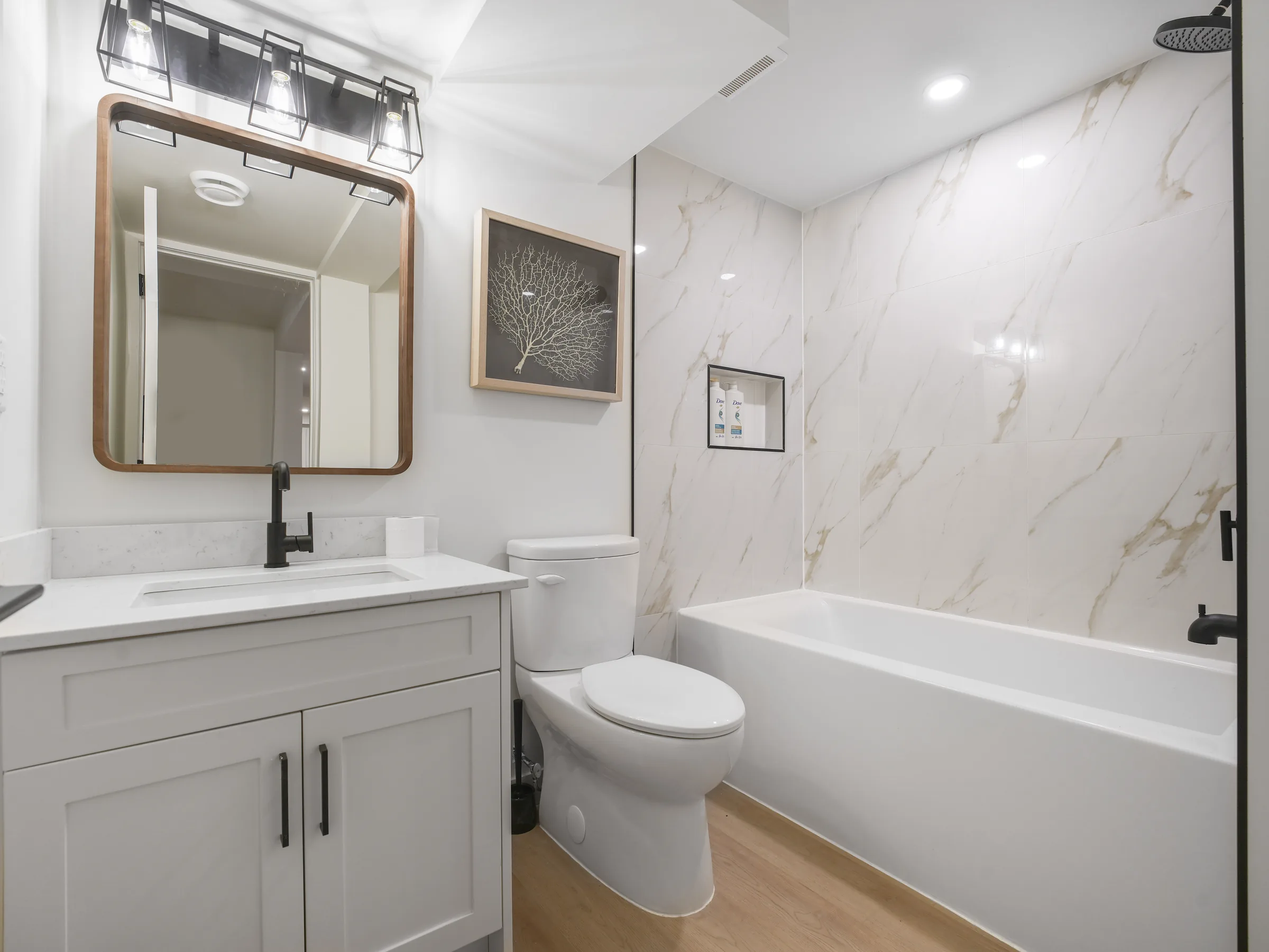 Full bathroom with marble-look tile tub/shower and coral art