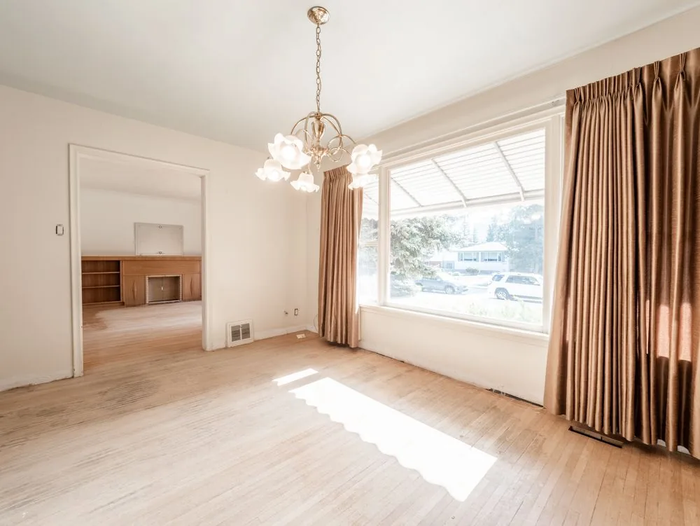 Before renovation, dining area with chandelier opening into the living room with fireplace