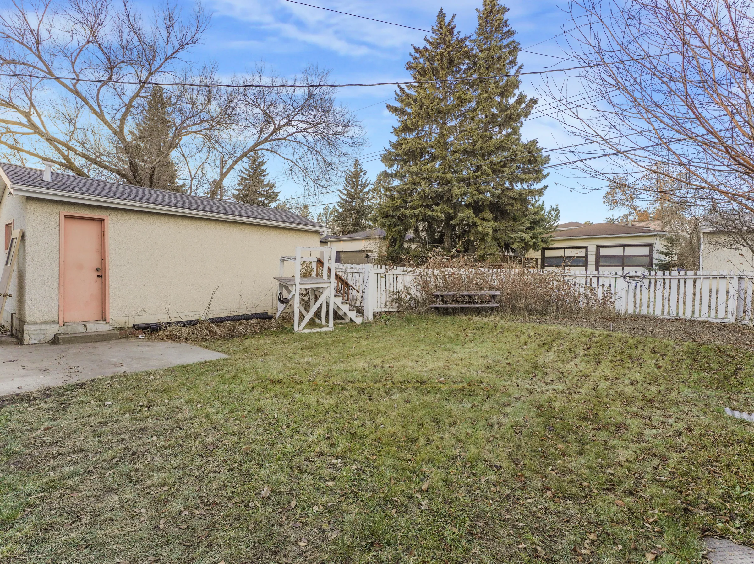Wide backyard shot toward the detached garage with pink door