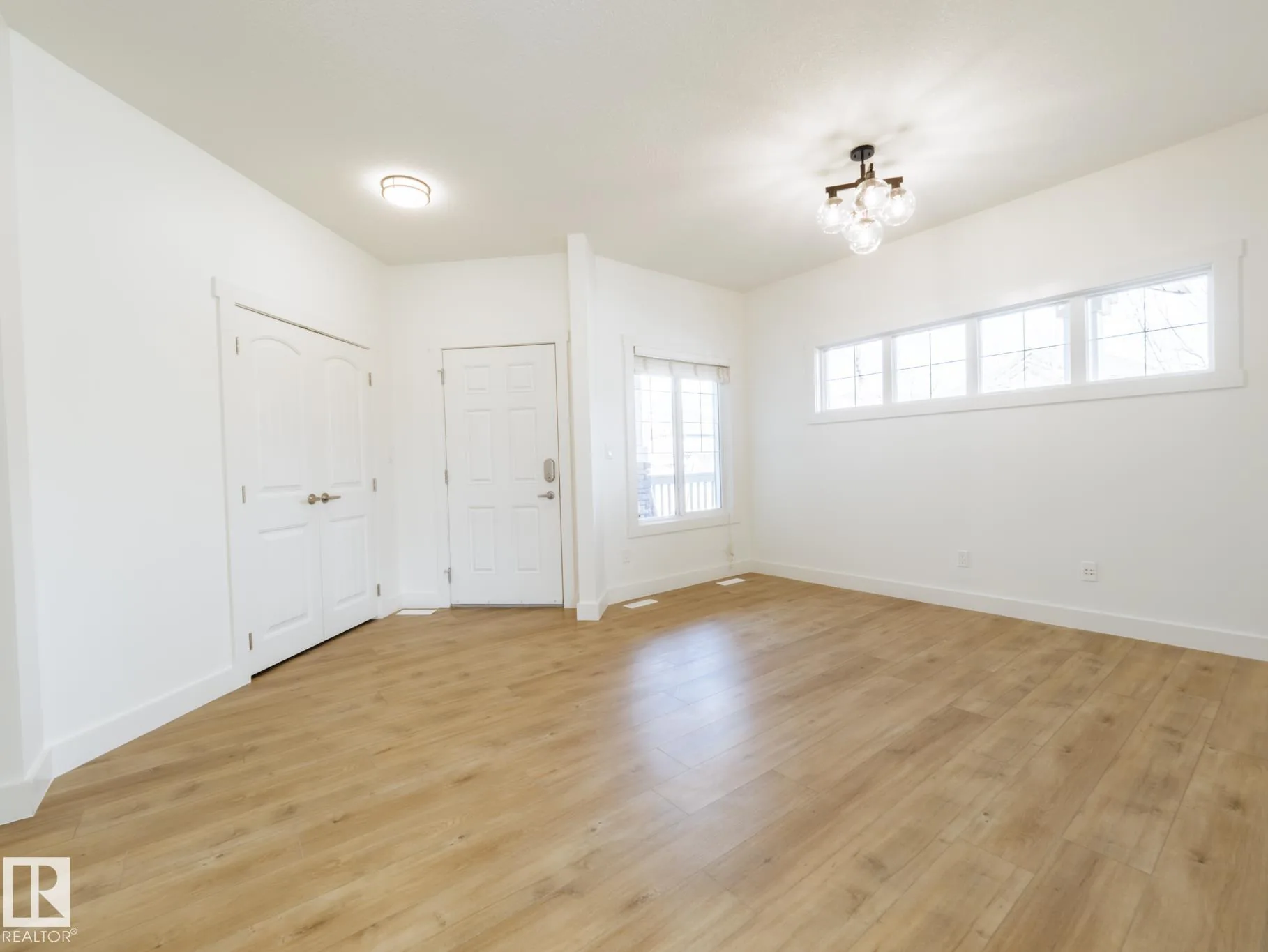 Front entry with paneled coat closet, keypad-lock door, and a new transom-window bank on the wall beyond