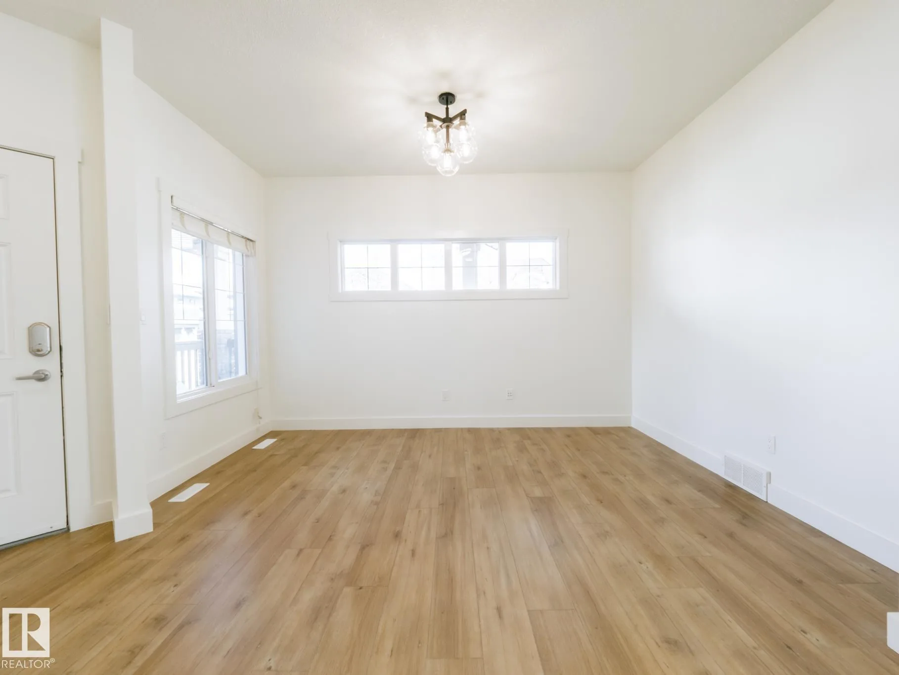 Dining space with a new globe chandelier and the preserved three-panel window bank on the far wall