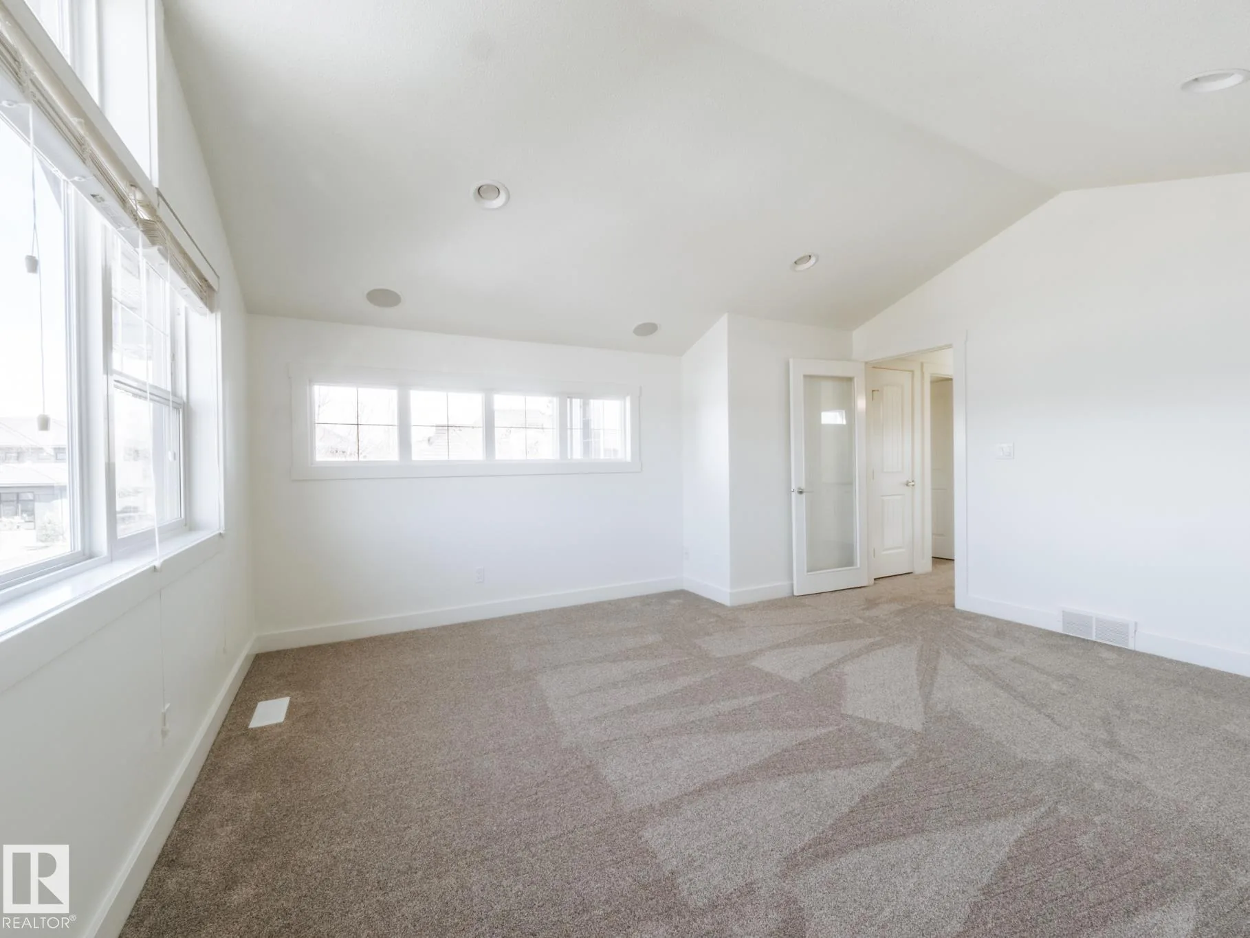 Primary bedroom with a vaulted ceiling and frosted-glass closet door
