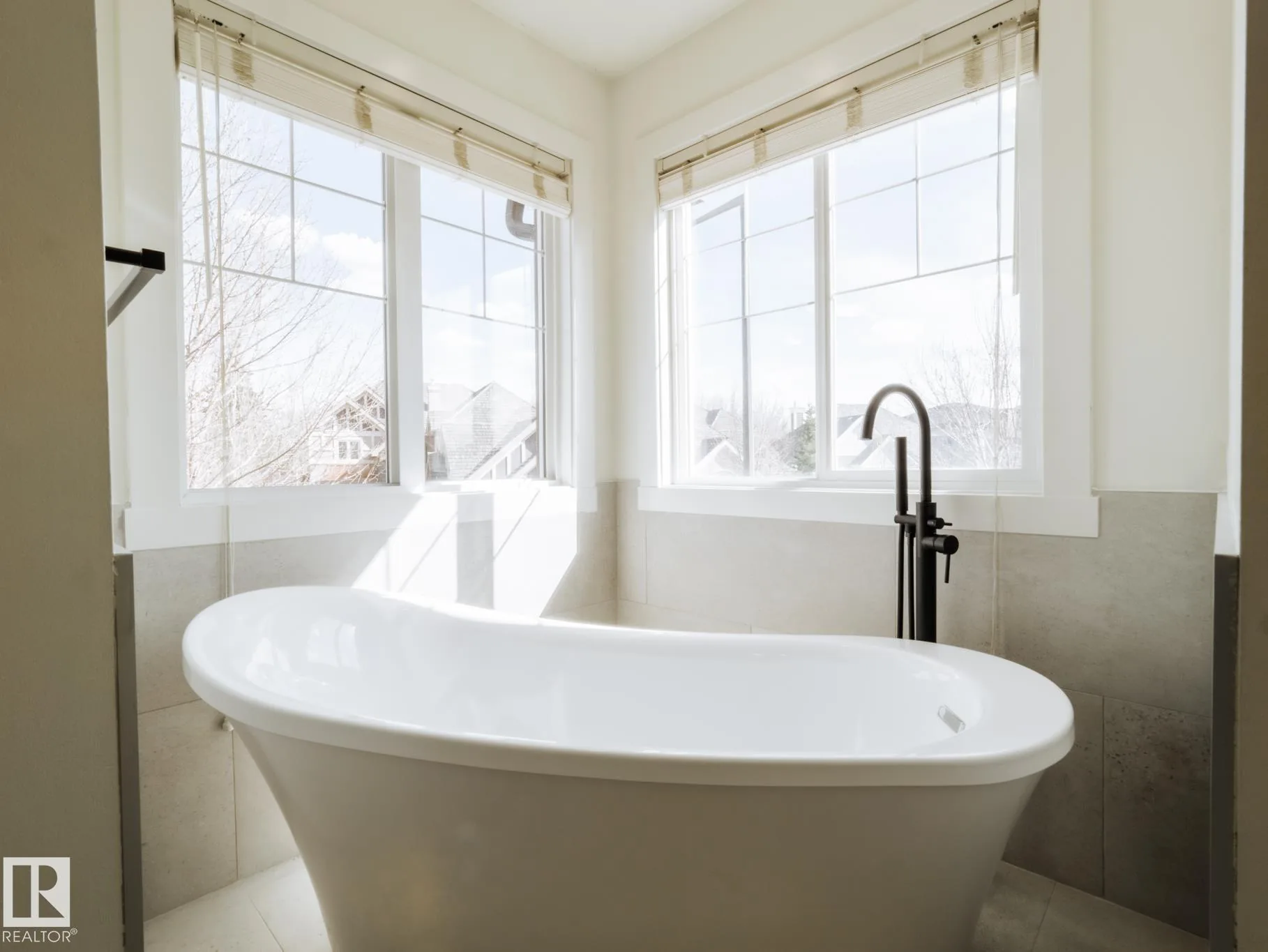 Freestanding oval tub set in the corner between two windows