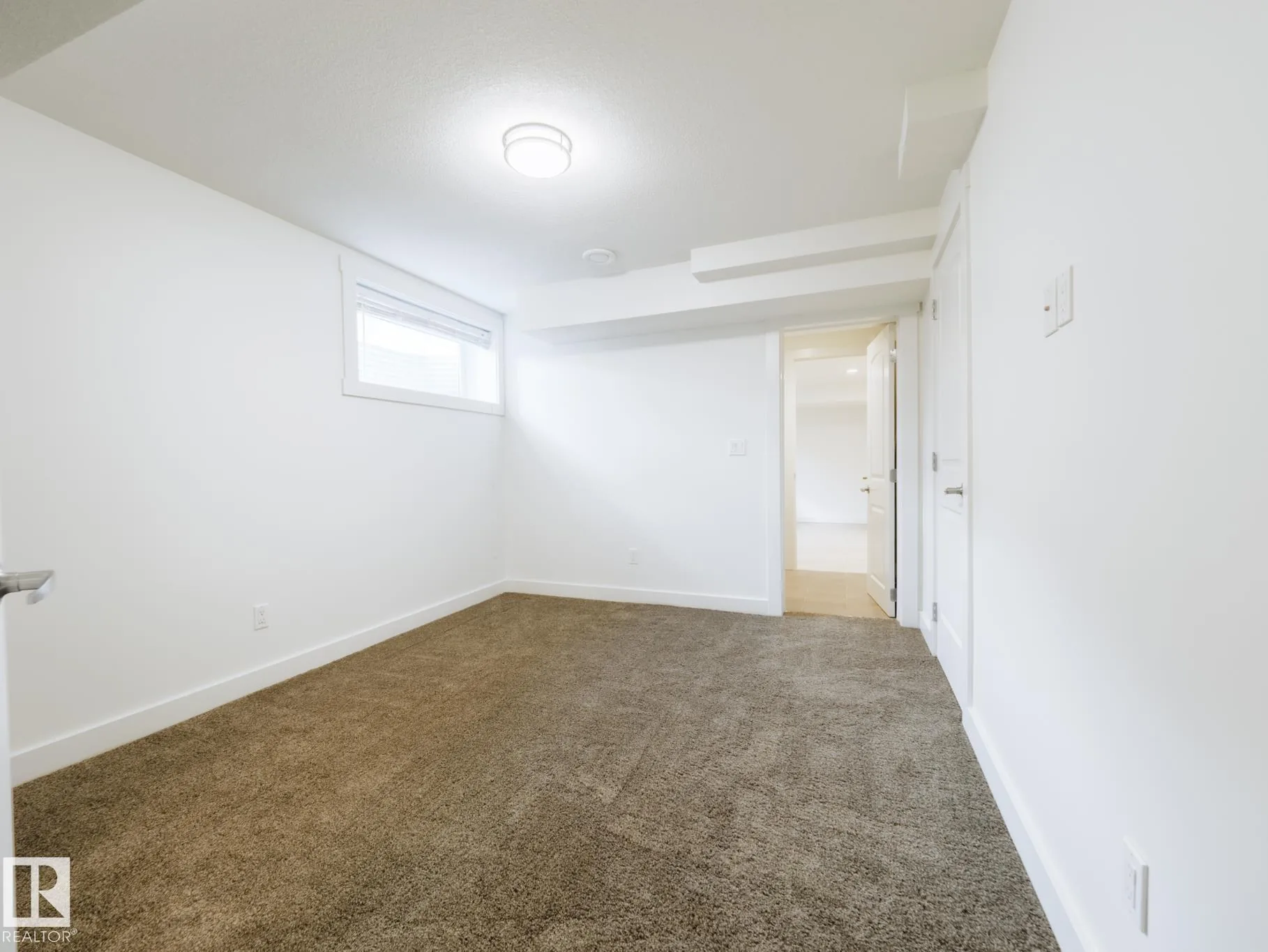 Basement bedroom with a single window and door to the tiled hallway